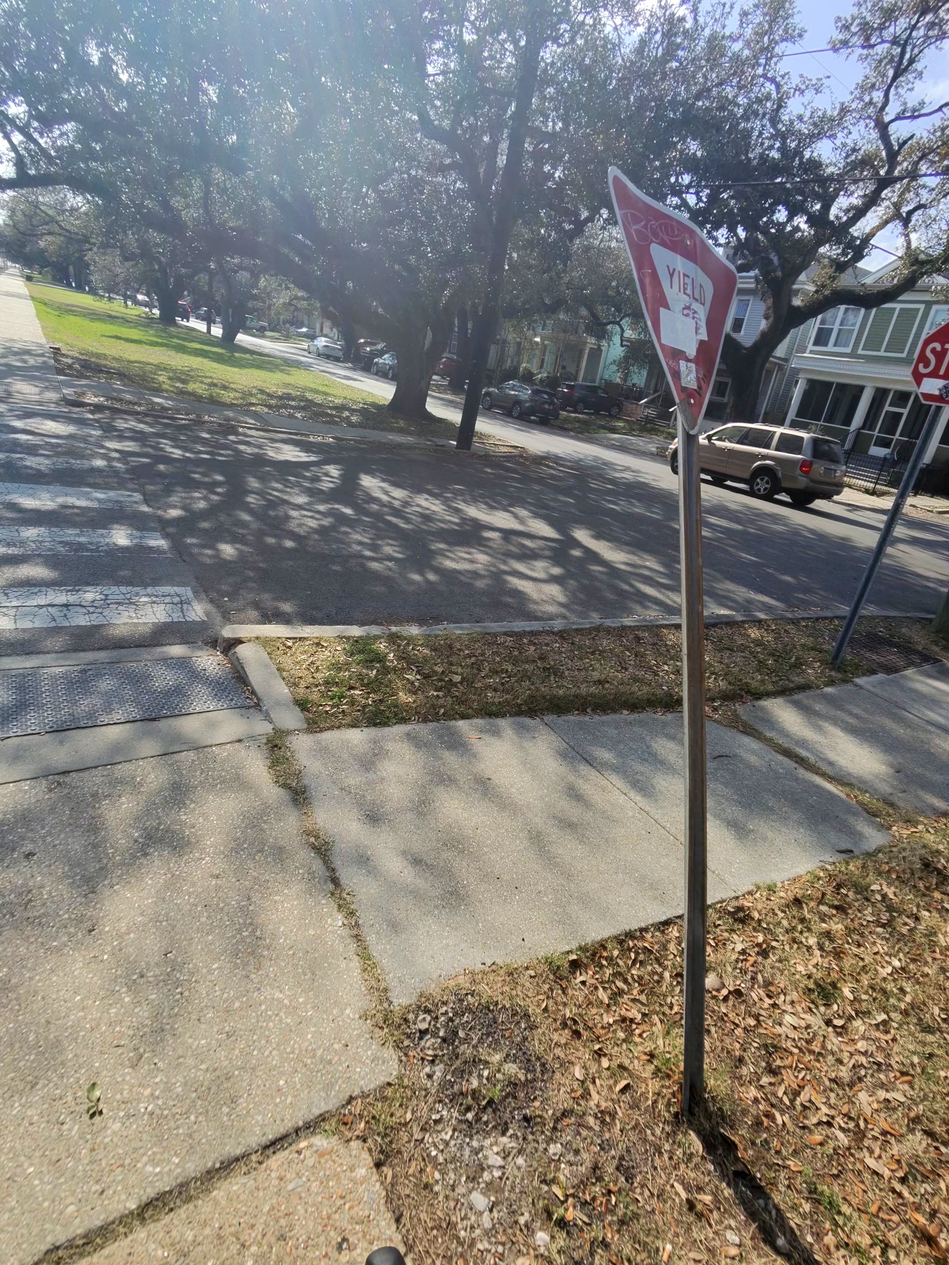 Cracked concrete path with a yield sign post obstructing the trail surface