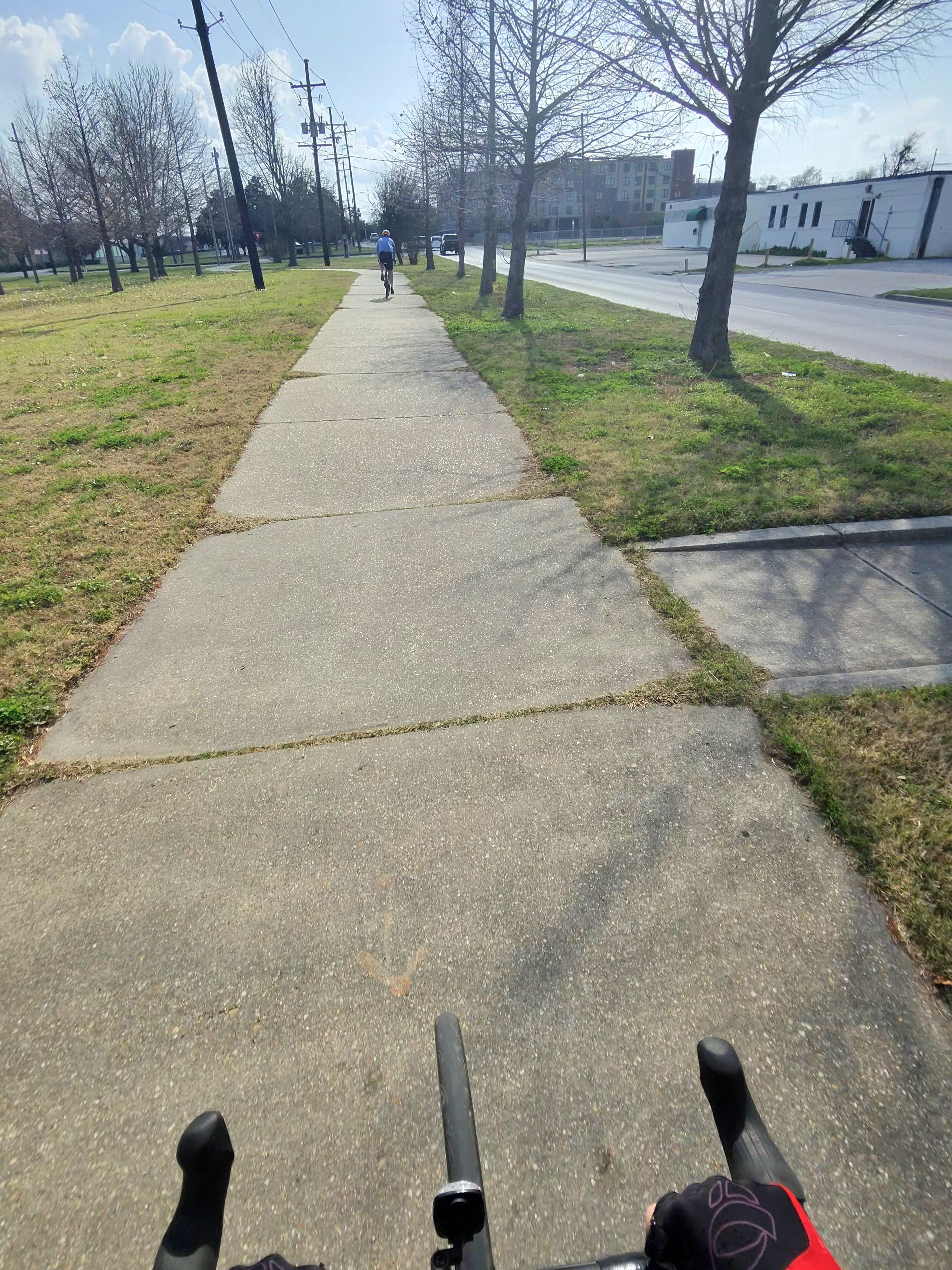 Narrow, uneven concrete path with visible seams and a cyclist riding ahead
