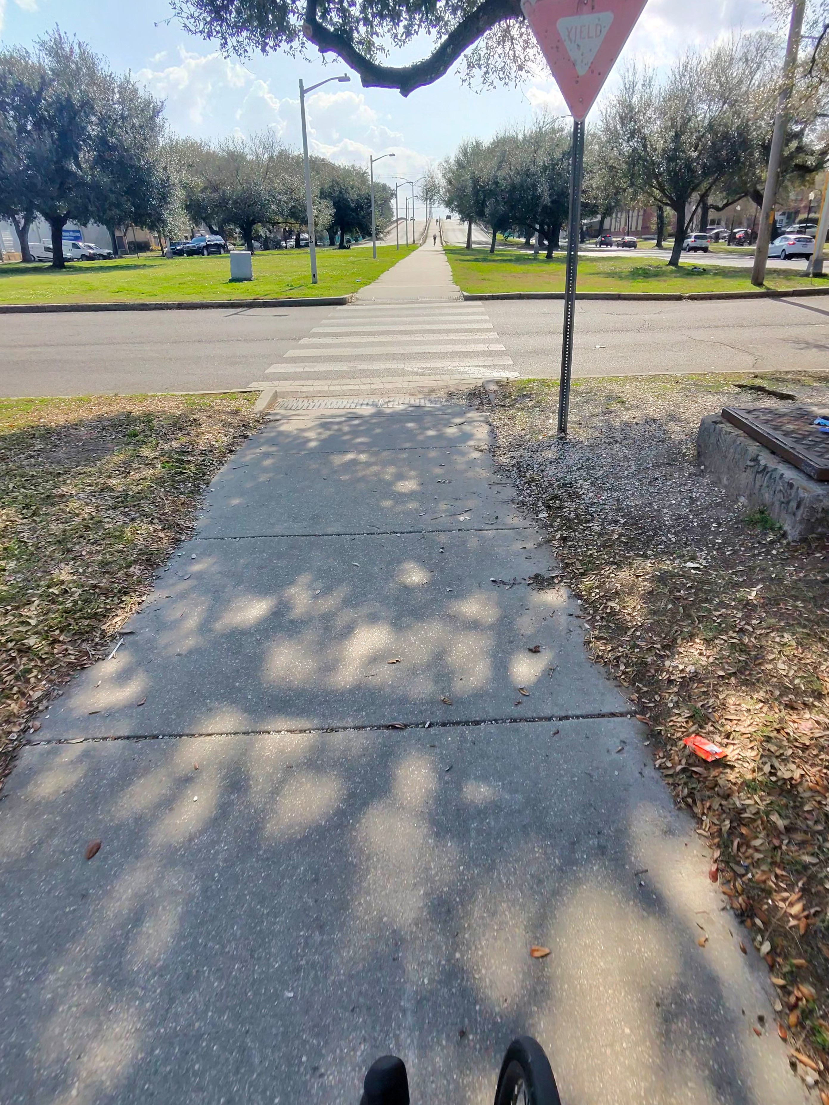 Rough path surface approaching a crosswalk with visible deterioration